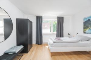 a white bedroom with a bed and a mirror at Moderne Ferienwohnung in Lorch in Lorch