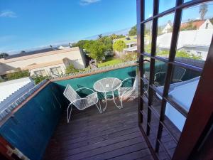 a balcony with a table and chairs next to a swimming pool at Whalers Guest House in Hermanus