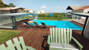 a deck with chairs and a table and a pool at Le Making Of Chambres d'Hôtes insolites et Familiales in Thairé