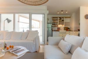 ein Wohnzimmer mit weißen Sofas und eine Küche in der Unterkunft Bel appartement lumineux à Biarritz in Biarritz
