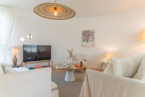 ein Wohnzimmer mit weißen Möbeln und einem Flachbild-TV in der Unterkunft Bel appartement lumineux à Biarritz in Biarritz