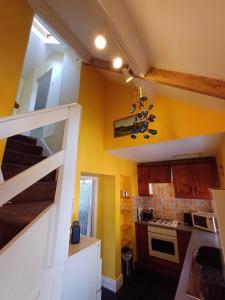 a small kitchen with yellow walls and a staircase at Simonside Cottage nr Rothbury in Morpeth