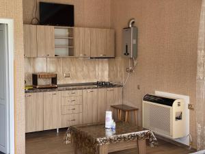kuchnia z drewnianymi szafkami, stołem i telewizorem w obiekcie Sweet House Rabati w Achalciche