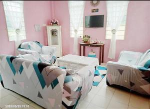 een roze kamer met witte stoelen en een tafel bij Diana Home @ Tuaran in Tuaran