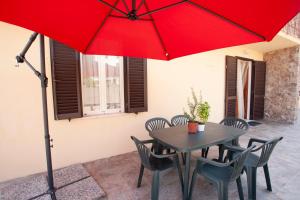 a table and chairs with a red umbrella at Villetta Capo Bianco - Goelba in Portoferraio