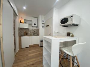 a small kitchen with a white counter and a table at Mon petit studio à la mer in Gruissan +7 photos