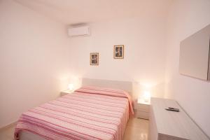 a white bedroom with a bed and a desk at Villetta Capo Bianco - Goelba in Portoferraio