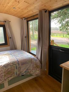 1 dormitorio con 1 cama y puerta corredera de cristal en Cosy Shepherd's Hut near Shrewsbury, 