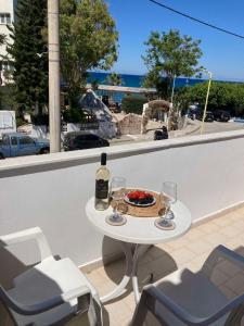 a table with wine glasses and a bowl of fruit on a balcony at SeaSide BayView in Faliraki