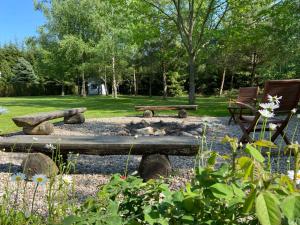 a fire pit in a park with two chairs and trees at Leniwa Kolonia in Sarnaki