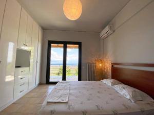a bedroom with a large bed and a large window at Sens de Dieu - Private luxury in Diakopto