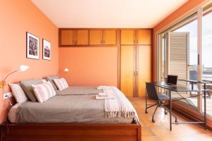 a bedroom with orange walls and a bed with a desk at Medano Seaview Penthouse CASA CORINA III in El Médano