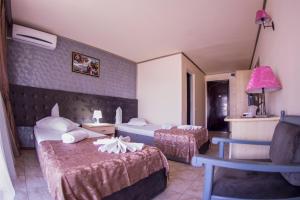 une chambre d'hôtel avec deux lits et une chaise dans l'établissement Voila Mamaia, à Mamaia