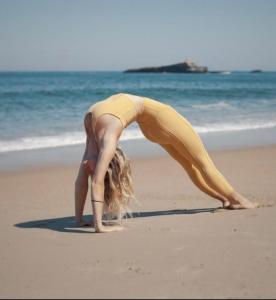 a woman doing a yoga pose on the beach at Hôtel Littéraire Jules Verne, BW Signature Collection in Biarritz