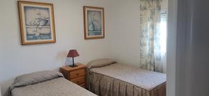 een slaapkamer met twee bedden en twee foto's aan de muur bij Apartamento con vistas en el centro de Mojácar in Mojácar