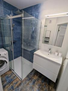 Un baño con lavabo y ducha de cristal. en Lovely 2-bedroom flat in the heart of Druskininkai, en Druskininkai 11 fotos más