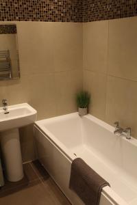 baño con bañera, lavamanos y planta en No2 Woodland View, en Bakewell