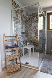 a glass shower with a chair and a table at Villa De Alberti in Vergiate