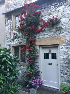 a stone house with a white door with red flowers at The Nook in Bakewell