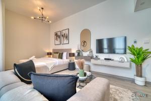 een woonkamer met een bed en een televisie bij Graceful Studio at Mesk 1 Midtown Dubai Production City by Deluxe Holiday Homes in Dubai