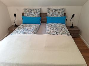 a bedroom with a white bed with blue pillows at Ferienhaus Altes Backhaus in Roetgen
