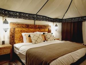 1 dormitorio con 1 cama grande en una tienda de campaña en Merzouga dreams Camp en Erfoud