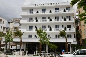 un hôtel blanc avec des arbres devant lui dans l'établissement Elite Hotel, à Golem