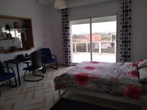 a bedroom with a bed and a desk and a window at Espace la Détente in El Jadida