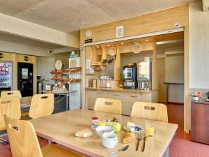 - une salle à manger avec une table et des chaises en bois dans l'établissement B&B HOTEL Clermont-Ferrand Gerzat, à Gerzat
