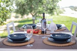una mesa con platos y copas y una botella de vino en Villa Dyria exclusive swimming pool, en Monopoli