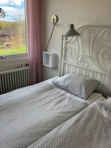 a bedroom with a white bed with a lamp and a window at Bergåsa bed & kitchen Drängsered in Torup