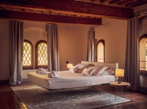 a bedroom with a large bed with two windows at Il Castello di San Ruffino in Lari
