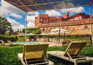 2 sillas y una piscina frente a un edificio en Il Castello di San Ruffino, en Lari