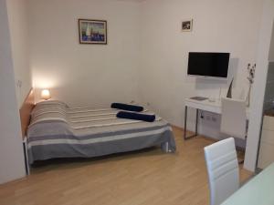 um quarto com uma cama e uma secretária com uma televisão em New Studio Apartments Trlaja em Sibenik
