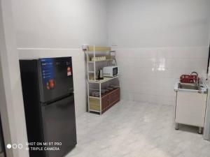 a kitchen with a black refrigerator and a shelf at NEW 55 Homestay Corner Lot Spacious House in Bukit Bakri Muar in Muar