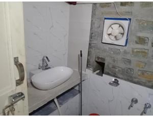 ein weißes Waschbecken im Bad mit einer Steinmauer in der Unterkunft Hotel Mud House Auli, Joshimath, in Jyotirmath