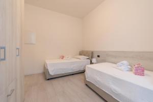 two beds in a room with white walls and wooden floors at Palazzetto La Quadra di San Faustino - F&L Apartment in Brescia