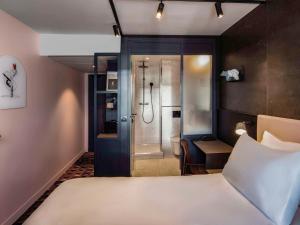 um quarto de hotel com uma cama e um chuveiro em TRIBE Paris Batignolles em Paris