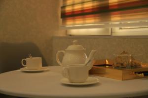 杜尚别Green Hotel Dushanbe的桌子上放着两个杯子,茶壶