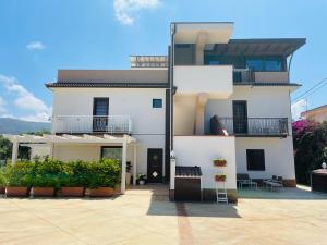 a white house with a balcony and plants at B&B Il Girasole in Capo dʼOrlando