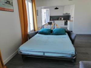 un letto con cuscini blu in una stanza di Le Barbatrin a Barbâtre
