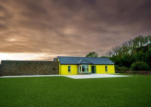 una casa gialla con un muro e un campo verde di Carrig Island Lodge a Ballylongford