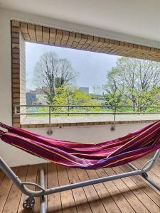 a hammock on a balcony with a large window at Superbe appartement avec 2 balcons - vue sur la cathédrale environ 15 min en tram-parking gratuit dans la rue in Strasbourg