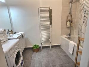 a bathroom with a washing machine and a bath tub at Superbe appartement avec 2 balcons - vue sur la cathédrale environ 15 min en tram-parking gratuit dans la rue in Strasbourg