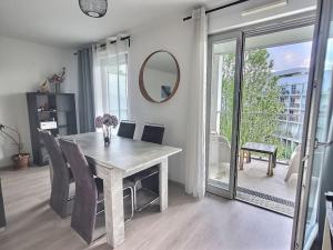 a dining room with a table and chairs and a mirror at Superbe appartement avec 2 balcons - vue sur la cathédrale environ 15 min en tram-parking gratuit dans la rue in Strasbourg