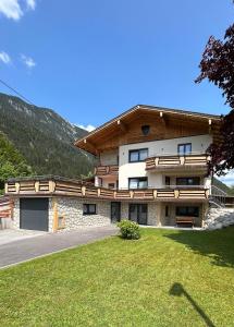 a large building with a grass yard in front of it at Ferienwohnungen LODGE-B in Weissenbach am Lech