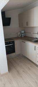 a kitchen with white cabinets and a black oven at Feel Good Apartment Rab in Mundanije