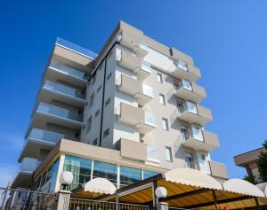 um edifício de apartamentos alto com um céu azul ao fundo em Hotel Harmony em Rimini
