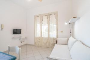 a white living room with a white couch and a tv at Villetta Bianca in Lampedusa