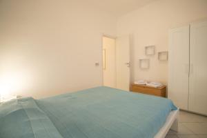 a white bedroom with a blue bed and a cabinet at Villetta Bianca in Lampedusa